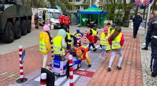 Policjanci uczą dzieci zasad ruchu drogowego na pikniku z okazji Dnia Drogowca